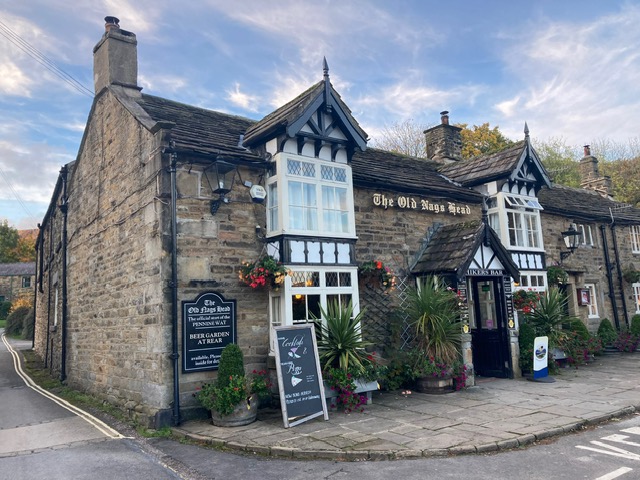Charming stone cottage with traditional architecture, featuring a welcoming pub entrance and vibrant floral displays