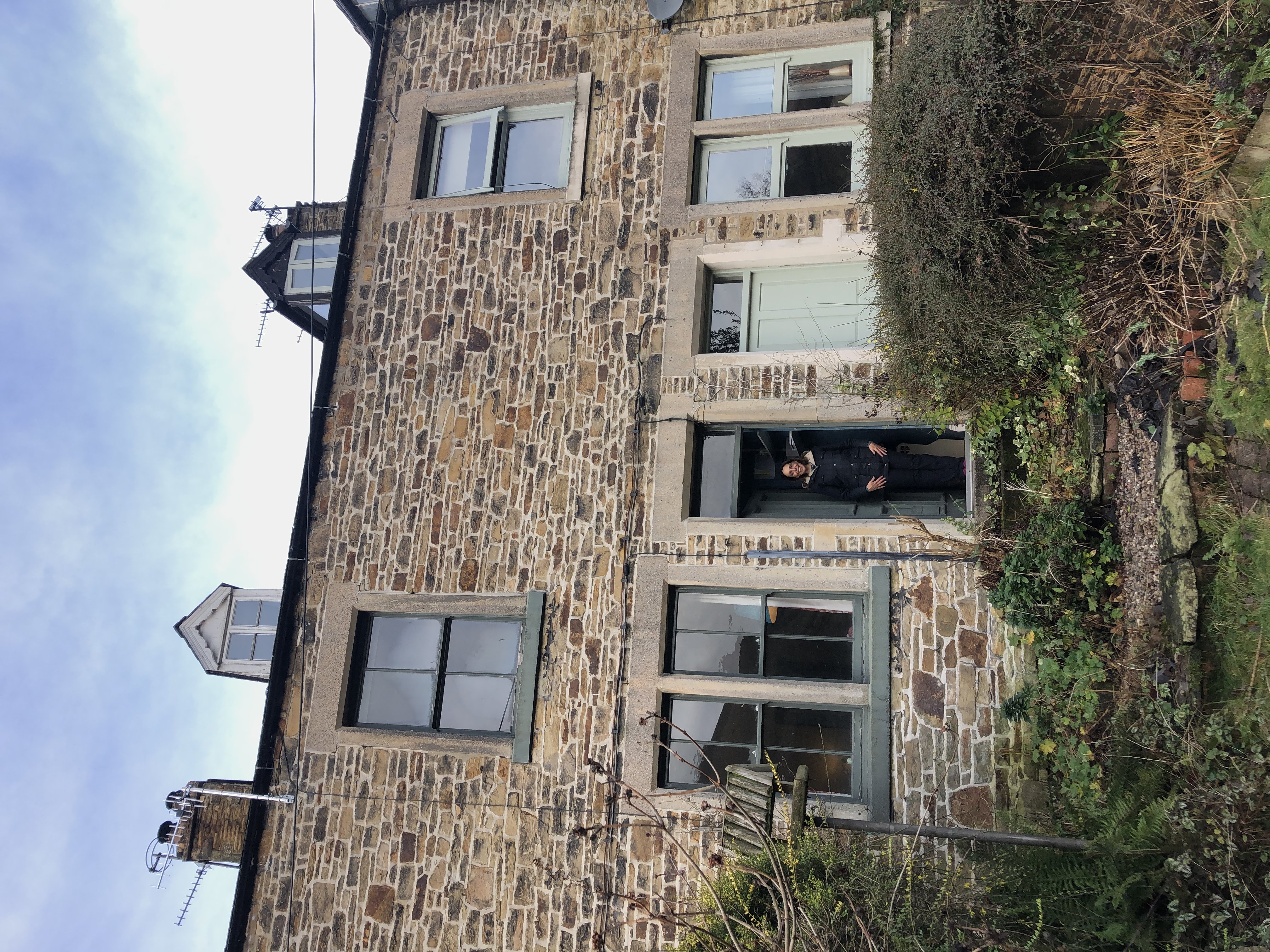 Stone cottage exterior with large windows, lush garden, and charming architectural details, perfect for a luxury getaway
