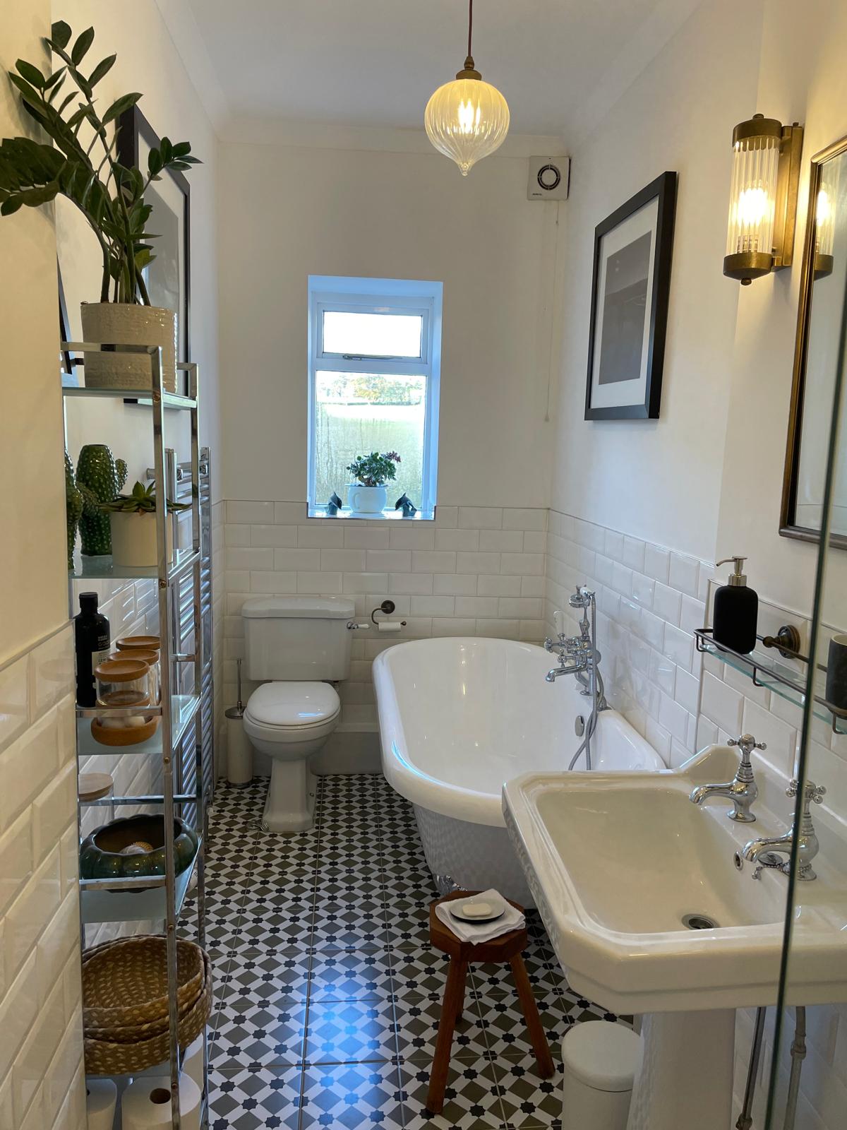 Luxury bathroom featuring a freestanding tub, elegant sink, stylish decor, and patterned floor tiles