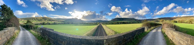 Scenic view of lush green fields and rolling hills under a bright sky, ideal for a luxury countryside retreat
